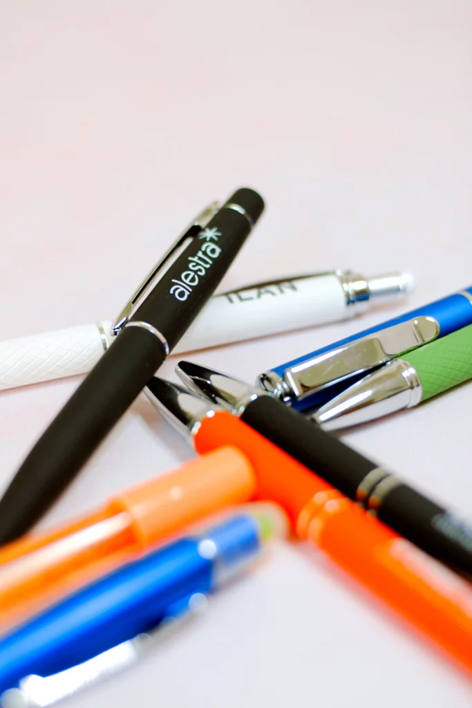 Fotografía de varios bolígrafos de diferentes colores que tienen un logotipo hecho con grabado láser.