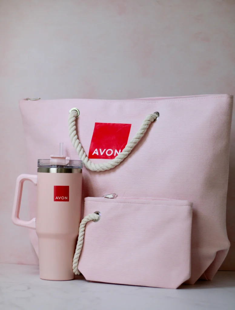 Fotografía de una bolsa, un neceser y un termo color rosa con un logotipo en color rojo y blanco hecho con grabado láser.