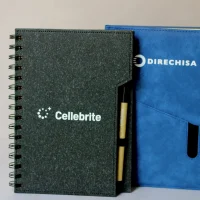 Fotografía de una libreta color azul junto a una libreta color gris que se hace con grabado láser en termos.