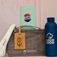 Fotografía de un cilindro, una bolsa, unos audífonos y una libreta personalizados con grabado láser en termos.